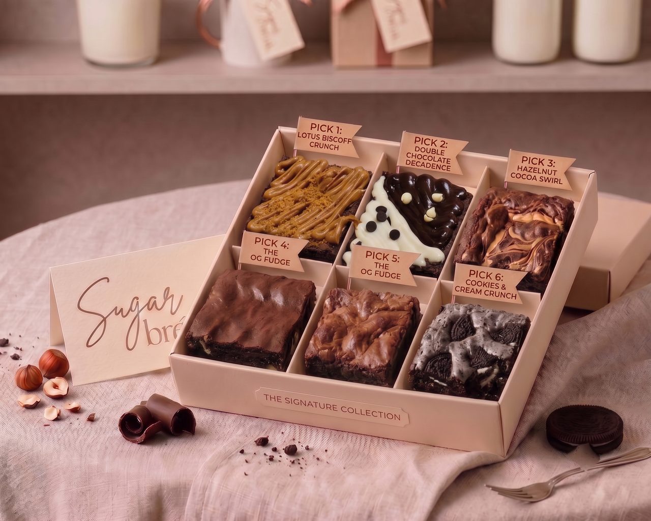 The Mixed Six, a six-compartment Sugar bréak signature box with labelled brownie picks across the five flavours and two slots left to fill, Sugar bréak card alongside